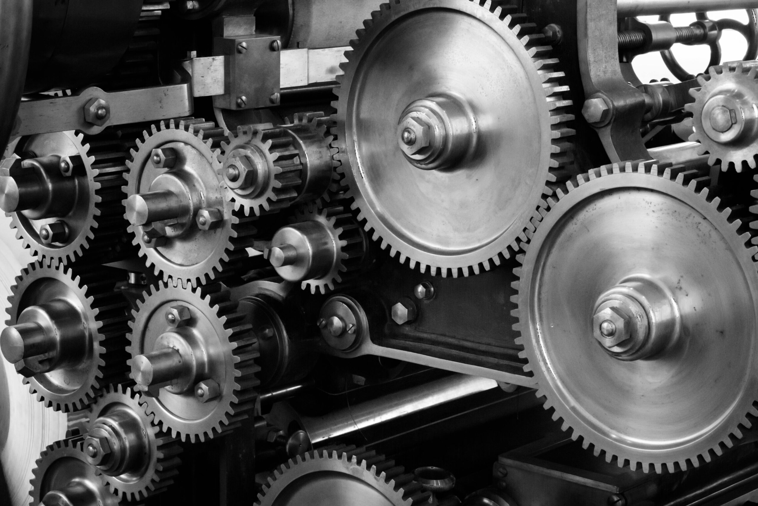 Close-up view of a complex industrial gear mechanism in black and white.