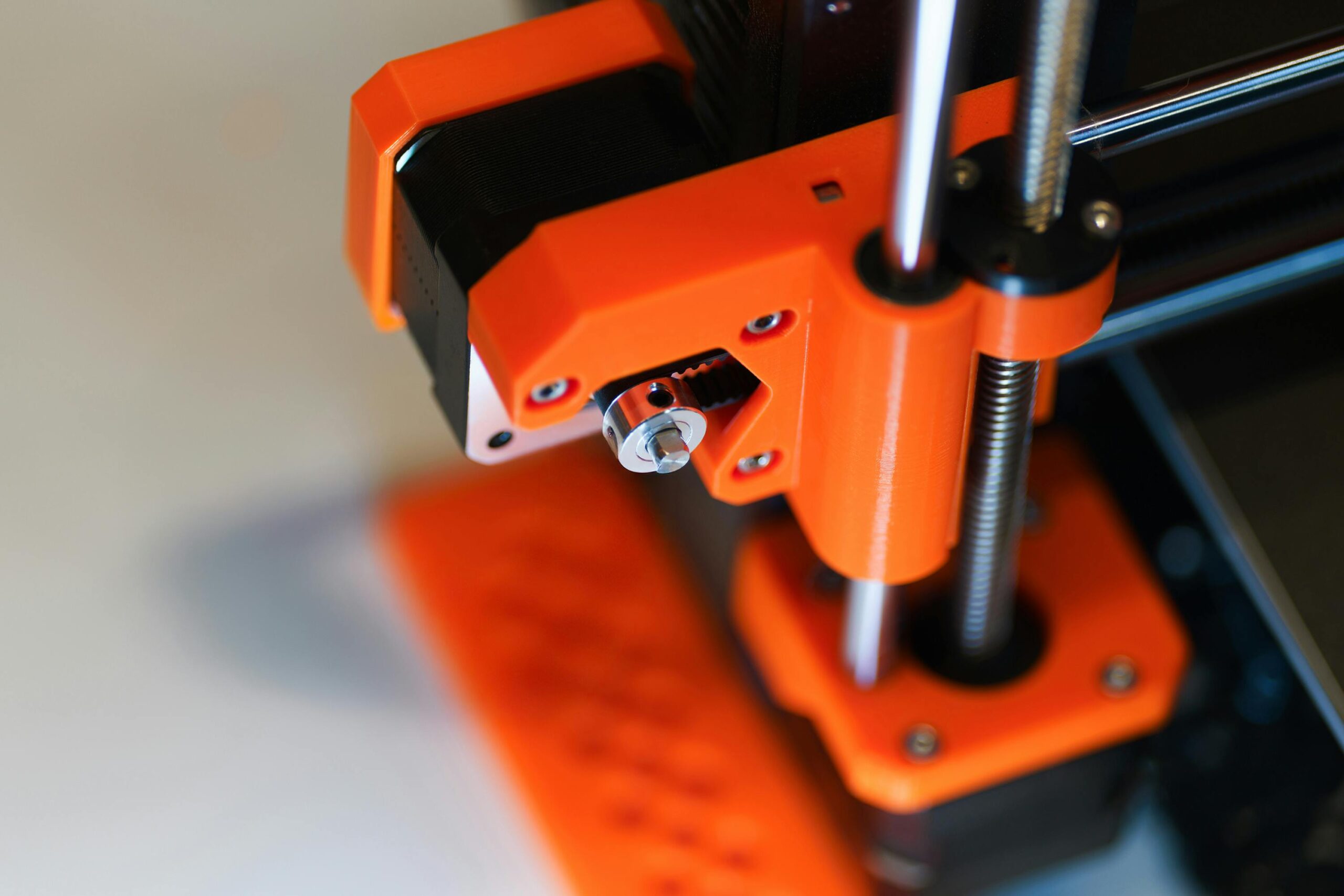 Detailed view of an orange 3D printer element with focus on mechanical parts.