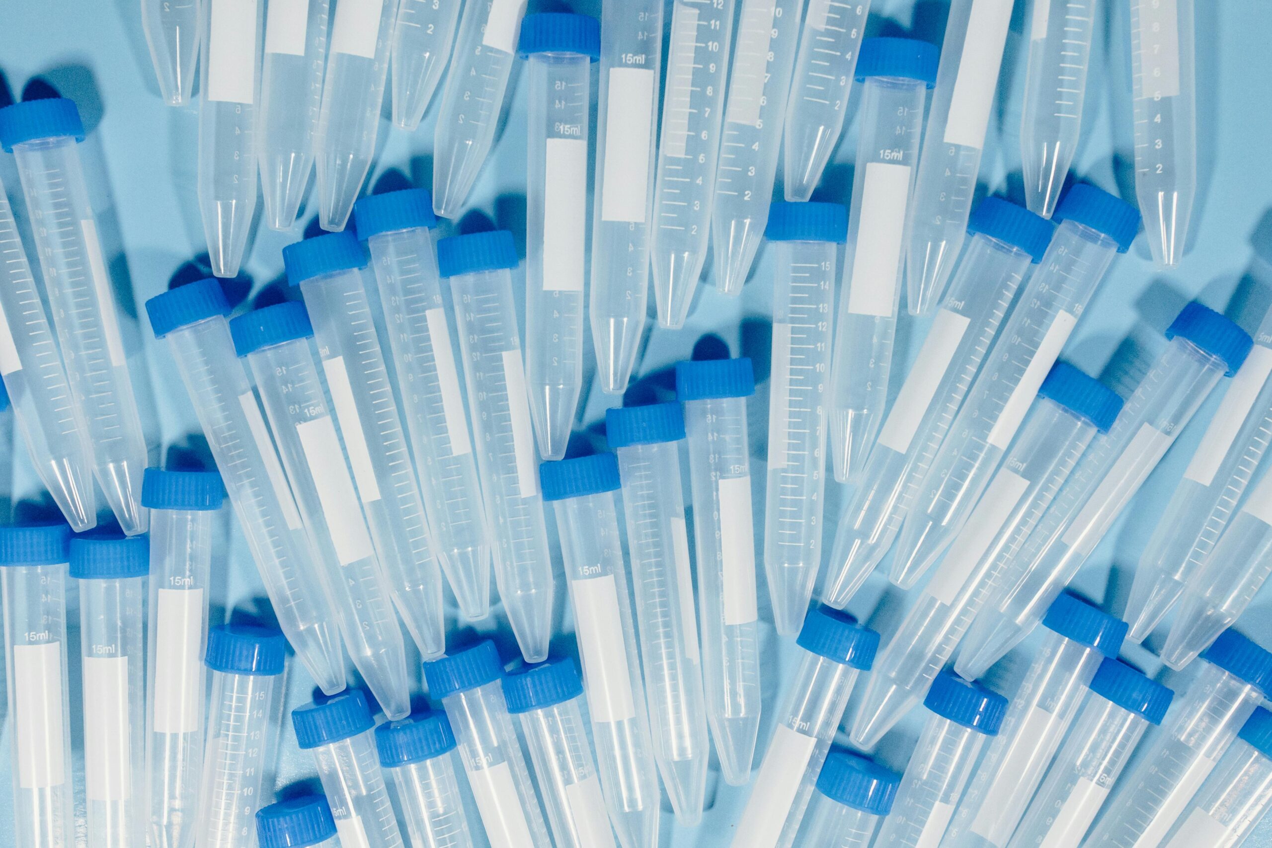 Numerous test tubes with blue caps arranged on a light surface, ideal for lab themes.